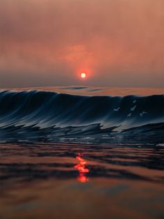 the sun is setting over an ocean wave