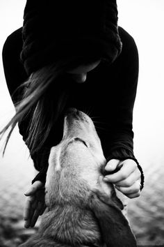 a woman is kissing the head of a wolf