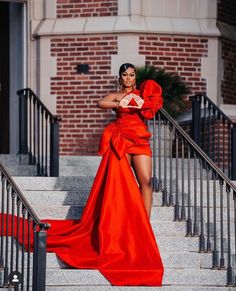 a woman in a red dress standing on some stairs