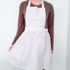 a woman wearing an apron standing in front of a white wall