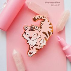 a tiger pin sitting on top of a pink surface