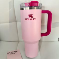 a pink tumbler cup sitting on top of a white table next to a tag