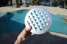 a person holding up a circular object near a swimming pool