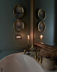 a bathroom sink sitting under a mirror next to a wall mounted faucet with candles on it