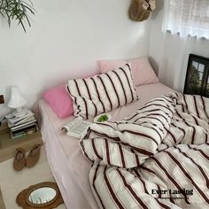 a bed with striped sheets and pillows on it