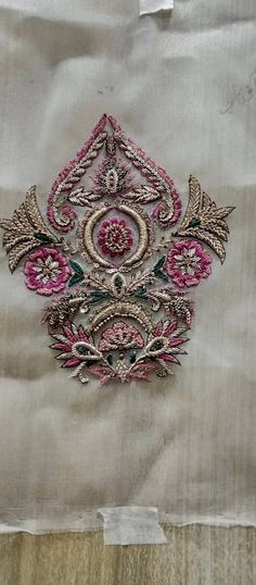 an embroidered piece of cloth with pink and green designs on it