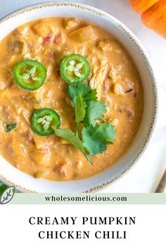 creamy pumpkin chicken chili with jalapenos and cilantro in a white bowl