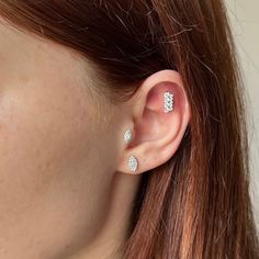 a close up of a person's ear with two diamond studs on it