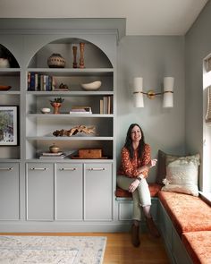 a woman sitting on a bench in front of a bookshelf