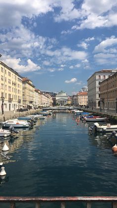 boats are parked along the side of a river in an old european city with tall buildings on both sides