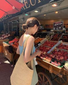 a woman standing in front of a fruit stand