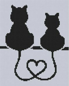 two black cats sitting on top of a table with a heart in front of them