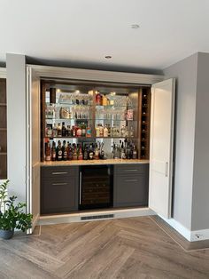 an empty bar with many bottles and glasses on the shelves, in a room with wood flooring