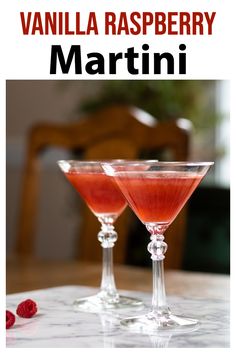 two martinis sitting on top of a table with raspberry in the background