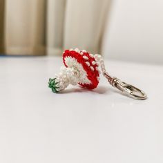 a crocheted keychain with a red, white and green flower on it