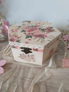 a wooden box sitting on top of a table covered in pink flowers and laces