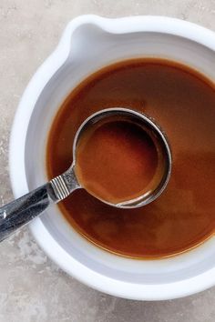 a white bowl filled with brown liquid and a spoon