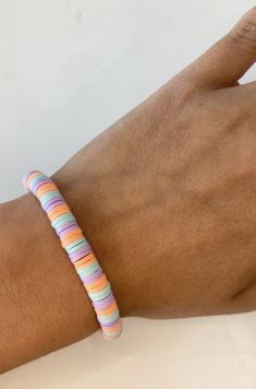 a person's hand wearing a bracelet with multicolored stripes on it and a white background