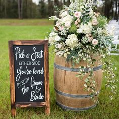 a wooden barrel with a chalkboard sign next to it and flowers in the middle