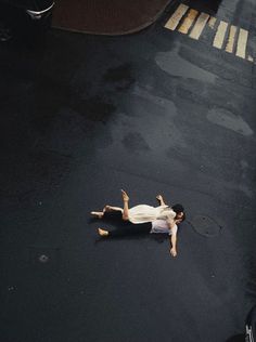 a person laying on the ground in the middle of the street with their arms outstretched