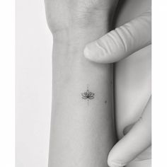 a woman's wrist tattoo with a lotus flower on the left side of her arm