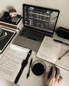 a laptop computer sitting on top of a desk next to notebooks and other items