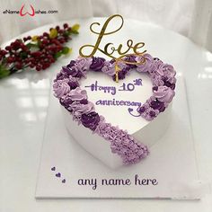 a white heart shaped cake with purple flowers on it