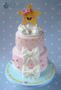 a three tiered cake with stars and bows on it's top is decorated in pastel colors