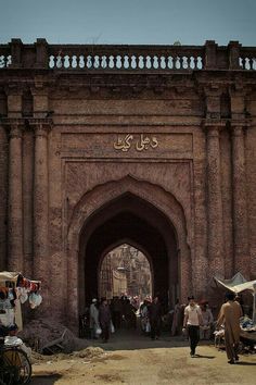 an old gate with people walking around it