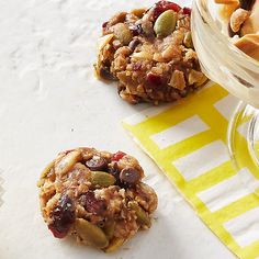 two cookies sitting on top of a table next to a bowl of fruit and nuts