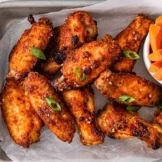 chicken wings in a tray with dipping sauce on the side and garnished with green leaves