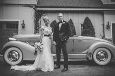 a bride and groom standing in front of an old car outside their wedding reception venue