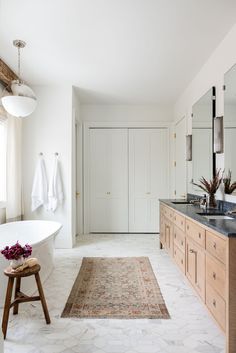 a bath room with a tub a sink and a rug on the floor in front of a window