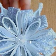 a person is holding a blue and white hair bow with sequins on it