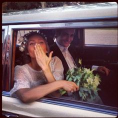 a man and woman sitting in the back seat of a car with their hands up to their face