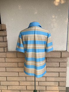 "Vintage 1970's women's polo style blouse in baby blue and camel stripe. Darted bust and top stitching accent. Excellent vintage condition! label: JC Penney Fashions fabric: n/a Feels like polyester size: n/a Size large is just an estimate. Please check measurements for an accurate fit. Questions are welcome! Top was measured across the front side lying flat. underarm to underarm 22\" length 27\" shoulder 16\"" Bombshell Dress, Hostess Apron, Half Apron, Striped Polo Shirt, Polo Style, Style Blouse, Button Up Top, Ruched Dress, Fashion Fabric