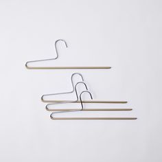 three metal clothes hangers on a white background with one hanging from the wall and another holding two wooden pegs