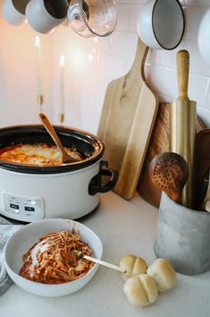 a crock pot filled with pasta and sauce next to other cooking utensils