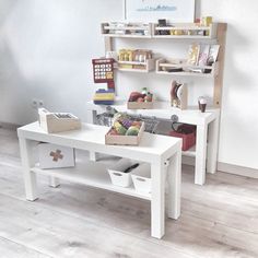 a white table with toys on it in front of a book shelf and wall mounted bookshelf