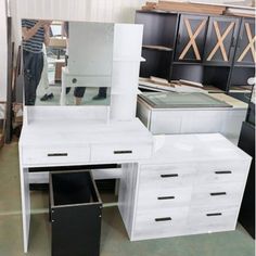 a white desk with drawers and a mirror on it in a room filled with furniture