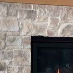 a fireplace with a fire burning in it's mantle next to a brick wall