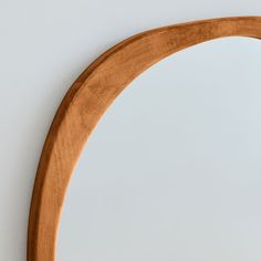 an oval wooden mirror hanging on the wall