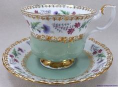 a tea cup and saucer with gold trimmings on the rim, decorated with flowers