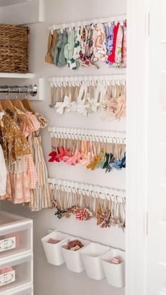 an organized closet with baby clothes hanging on the wall and other items in bins