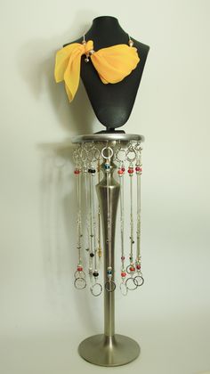 a mannequin with jewelry hanging from it's sides on a metal stand