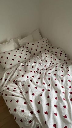 an unmade bed with red hearts on it