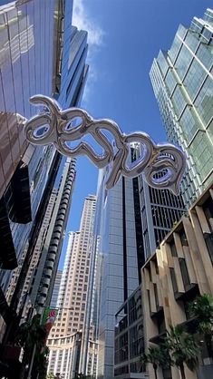 a large metal snake sculpture is in the middle of a city street with tall buildings