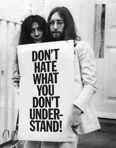 two people holding a sign that says don't hate what you don't under stand