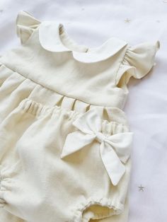 Cream Cotton Bubble Romper With Short Sleeves, Cream Short Sleeve Bubble Romper For Summer, Fitted Cream Bubble Romper With Ruffles, Cream Fitted Bubble Romper With Ruffles, Cute Cream Bubble Romper With Ruffles, Cotton Bubble Romper With Short Sleeves For Baptism, Cute Cream Cotton Bubble Romper, Cream Sleeveless Bubble Romper With Ruffles, Cute Beige Ruffled Bubble Romper