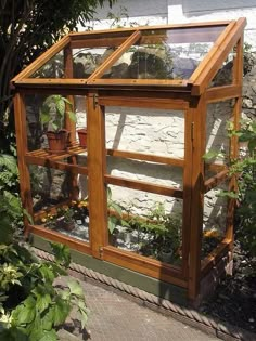 a small wooden greenhouse with plants growing inside